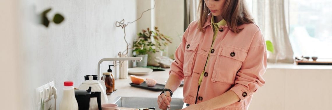 A woman slices an avocado in a bright, modern kitchen with natural light.