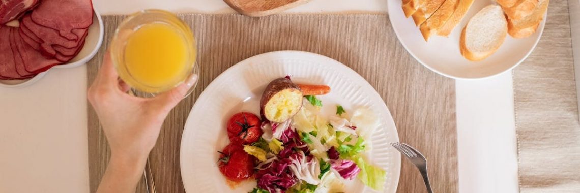 A top-view of a delicious breakfast setting featuring a salad, bread, cheese, tomatoes, and orange juice.
